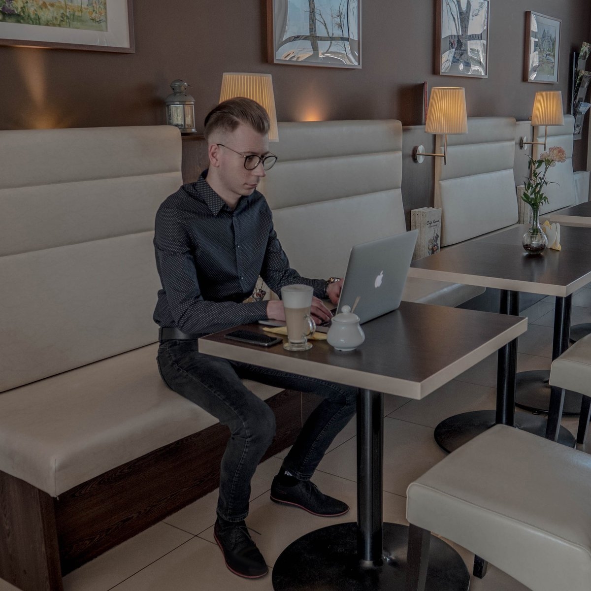 Mateusz Wróblewski programuje w kawiarni na swoim laptopie.
